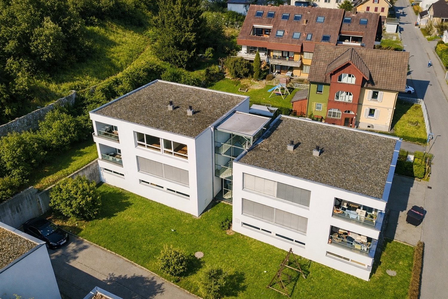 Luftbild einer Wohnanlage aus zwei weißen Mehrfamilienhäusern mit Garten
